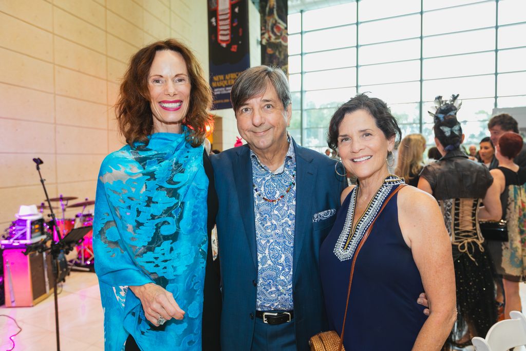 Eugenie Bondurant, Paul Wilborn, and Mary Rachel Quinn stand together smiling at the 2026 MUSE Awards, with fellow guests and musicam instruments behind them at the Museum of Fine Arts, St. Pete, FL.